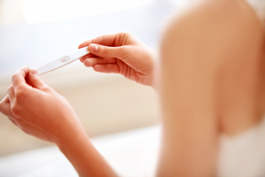 Woman Holding Positive Pregnancy Test After Calculating Ovulation